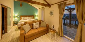 a bedroom with a bed and a couch in front of a window at The Olive Hill Guesthouse in Batalha