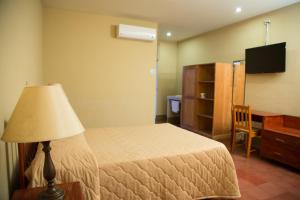 1 dormitorio con 1 cama con lámpara y escritorio en Hotel Frontera, en Ocotal