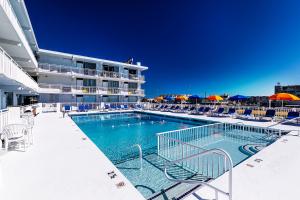 einen Pool mit Stühlen und Sonnenschirmen neben einem Hotel in der Unterkunft Crusader Oceanfront Resort in Wildwood Crest