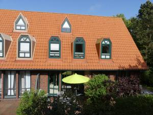 an orange roofed house with an umbrella in front of it at Ferienresidenz Austernfischer I/Nr. 2 in Spiekeroog