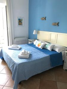 um quarto azul com uma cama com toalhas em Il Miraggio em Fregene
