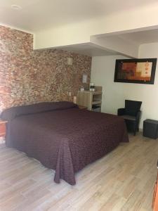 een slaapkamer met een bed en een bakstenen muur bij Bon Jesus Hotel in Costa Esmeralda