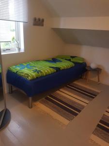 a bed sitting in a room next to a window at Lille Villa Severin in Mosterhamn