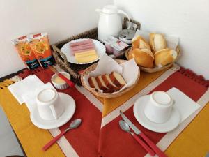 une table avec des assiettes et des tasses et une corbeille de pain dans l'établissement Suítes Recanto cama e café, à Arraial do Cabo