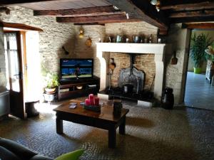 a living room with a fireplace and a tv at CHAMBRE A LA CAMPAGNE - CHARENTE in La Rochette