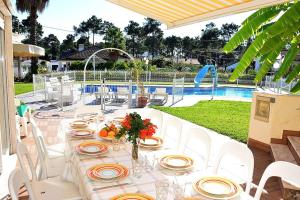 uma mesa longa com cadeiras brancas e uma piscina em Villa Verdizela II em Carcereiro