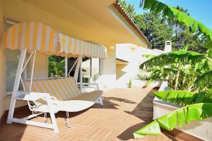 a porch with a chair and an umbrella at Villa Verdizela II in Carcereiro