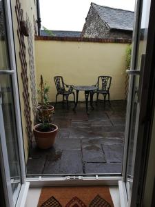 an open door with a patio with two chairs and a table at 6 beili priory in Abergavenny