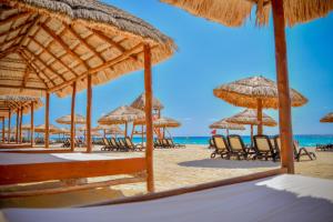 a beach with chairs and umbrellas and the ocean at Emporio Cancun - Buy All Inclusive Option in Cancún
