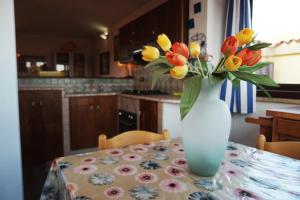 Appartamento Sardegna في بورتو سان باولو: إناء من الزهور على طاولة في مطبخ