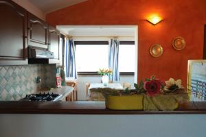 Appartamento Sardegna في بورتو سان باولو: مطبخ بجدران برتقالية وكاونتر عليه زهور