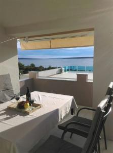 a table with a plate of fruit and a view of the ocean at Korina Apartments Mandre in Mandre