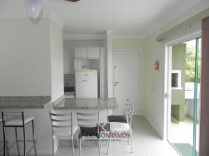 cocina con encimera con sillas y mesa en 1028 - Bombinhas para aluguel de temporada - Residencial Areia Branca 201, en Bombinhas