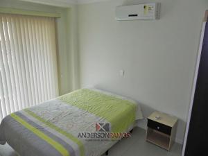 Dormitorio pequeño con cama con manta verde en 1028 - Bombinhas para aluguel de temporada - Residencial Areia Branca 201, en Bombinhas