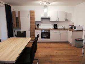 a kitchen with a wooden table and white cabinets at Ferienwohnung Schmied 1 in Aurach am Hongar