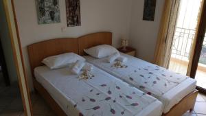 ニキティにあるNatalia's Apartmentsのベッドルーム1室(白いシーツと蝶が飾られた大型ベッド1台付)