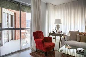- un salon avec une chaise rouge et un canapé dans l'établissement GRAN APARTAMENTO PLAZA DE ESPAÑA, à Séville