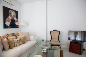 a living room with a white couch and a tv at GRAN APARTAMENTO PLAZA DE ESPAÑA in Seville