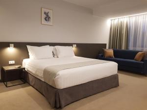 1 dormitorio con 1 cama grande y 1 sofá azul en NOVO Boutique, en Râmnicu Vâlcea