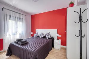ein Schlafzimmer mit einem Bett mit einer roten Wand in der Unterkunft Ever House - ALCALA DIVA 1 ROOFTOP in Madrid