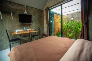 a bedroom with a bed and a table and a window at BR2 House Resort in Phayao