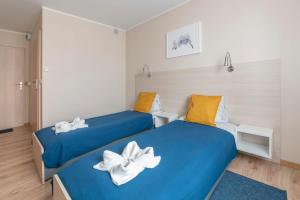 two beds in a room with blue sheets and yellow pillows at Willa Głogowska in Poznań