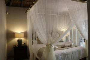 a bedroom with a canopy bed with white curtains at Luvivane Luxury Villa in Marloth Park