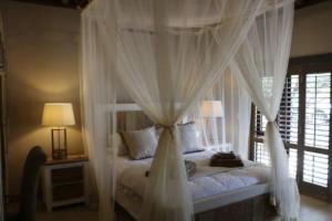 a bedroom with a canopy bed with white curtains at Luvivane Luxury Villa in Marloth Park