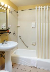 a bathroom with a white tub and a sink and a shower at Carlton Inn Midway in Chicago