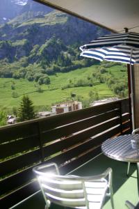 balcone con tavolo, sedie e ombrellone di Alfa Appartements Superior a Leukerbad