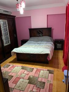 a bedroom with a bed with a pink wall at mody appartment at alexandria in Alexandria