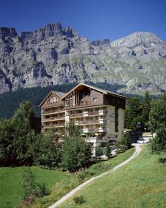 a building on a hill with a mountain in the background at Alfa Appartements Superior in Leukerbad