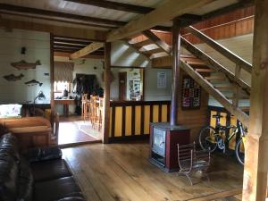 La Casona Puelo Lodge في كوشامو: غرفة معيشة مع موقد خشبي ودرج