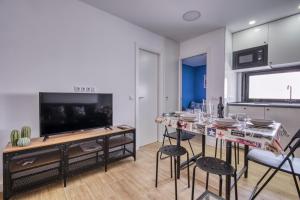 Ever House - ALCALA DIVA 2 ROOFTOP في مدريد: غرفة معيشة مع طاولة مع كراسي وتلفزيون بشاشة مسطحة