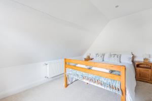 a bedroom with a wooden bed with white walls at Church Farm Cottage in Cheltenham