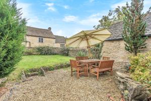 a table and chairs with an umbrella in a yard at Church Farm Cottage in Cheltenham