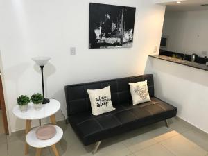 uma sala de estar com um sofá preto e uma mesa em Jardines del Boulevard 2 em Córdoba