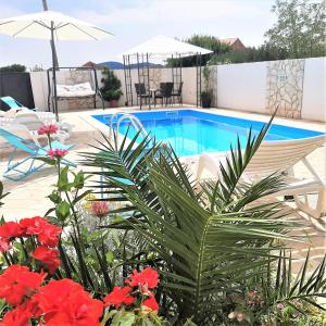 eine Terrasse mit einem Pool und Blumen in der Unterkunft Apartments"Nika" with private pool in Galovac