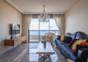 uma sala de estar com um sofá azul e uma mesa em Oַ&O Group- Mini Penthouse 3BR Sea View Bat-Yam em Bat Yam