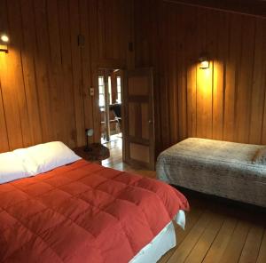 a bedroom with two beds and wood paneled walls at La Casona Puelo Lodge in Cochamó