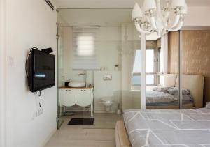 a bedroom with a bed and a tv and a bathroom at Oַ&O Group- Mini Penthouse 3BR Sea View Bat-Yam in Bat Yam