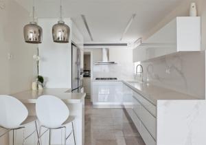 uma cozinha branca com armários brancos e bancos brancos em Oַ&O Group- Mini Penthouse 3BR Sea View Bat-Yam em Bat Yam