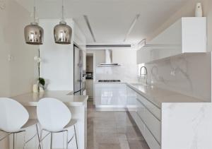 a white kitchen with white cabinets and white stools at Oַ&O Group- Mini Penthouse 3BR Sea View Bat-Yam in Bat Yam