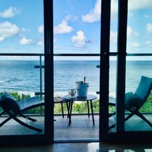 ミエンジズドロイェにあるBluMare apartament z widokiem na morzeのテーブルと椅子が備わる客室で、海の景色を望めます。