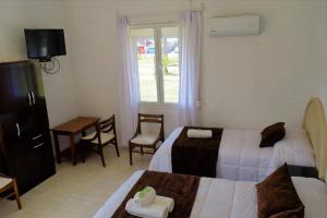 Habitación de hotel con 2 camas, mesa y ventana en Hotel Cabo Santa Maria, en La Paloma