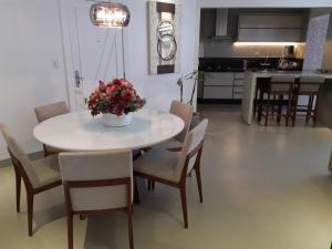 einen Esstisch und Stühle mit einer Blumenvase in der Unterkunft Balneário Camboriú in Balneário Camboriú + 4 Fotos