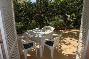 a table and chairs on a porch with trees at Apartments and rooms Jagoda - comfy and cozy in Zadar