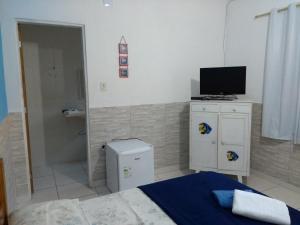 a bedroom with a bed and a television on a cabinet at Suítes Veleiro in Ubatuba