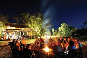 a group of people sitting around a fire at night at Bungle Bungle Wilderness Lodge in Turkey Creek