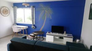 una sala de estar con sofá y una palmera en una pared azul en La Kay'Loulou avec spa et piscine, en Saint-Pierre